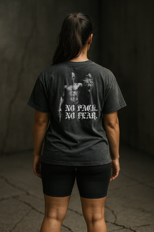 Person wearing a faded black t-shirt with 'No Pack, No Fear' text on the back against a dark background.