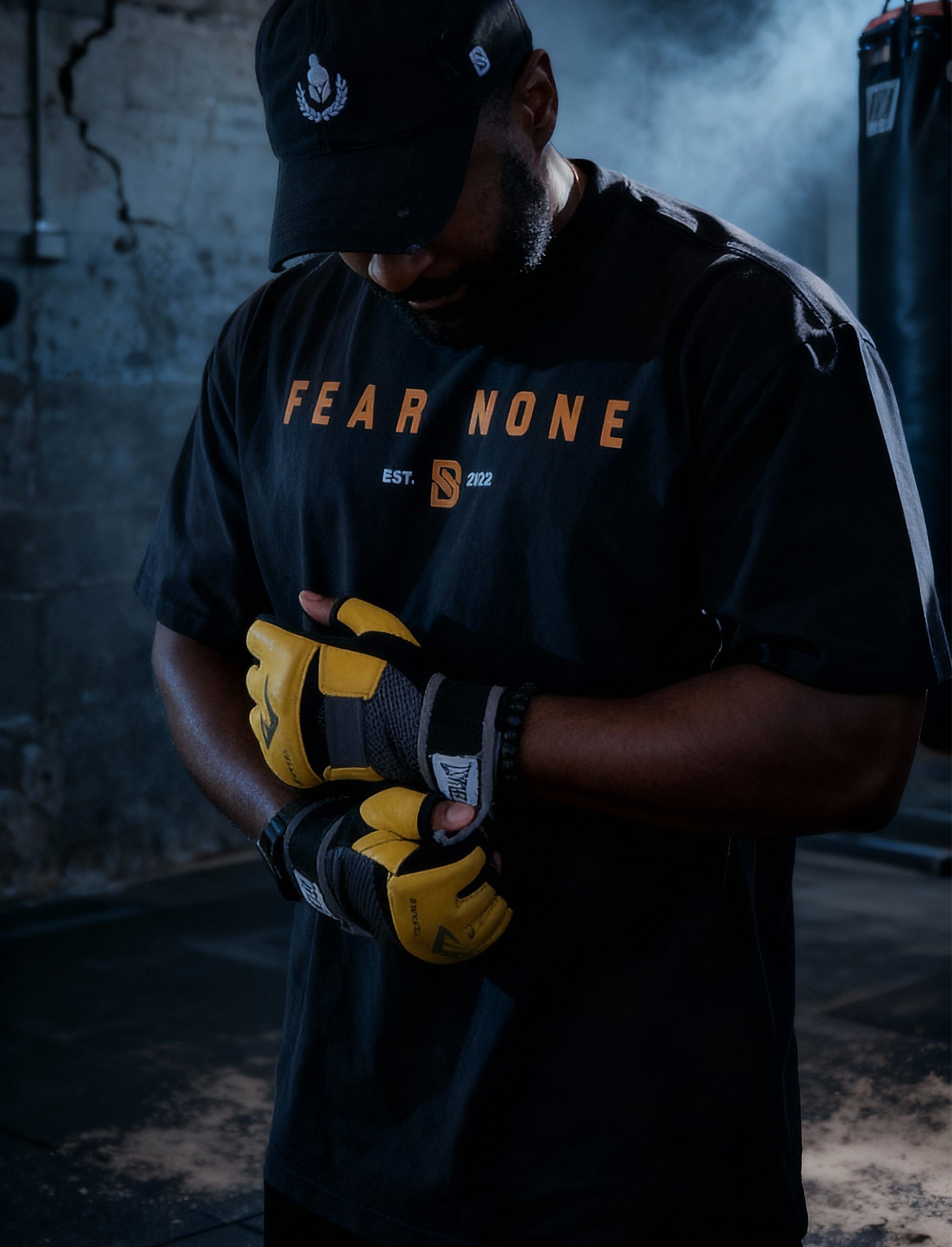 Person wearing a 'Fear None' t-shirt and gloves in a dark setting