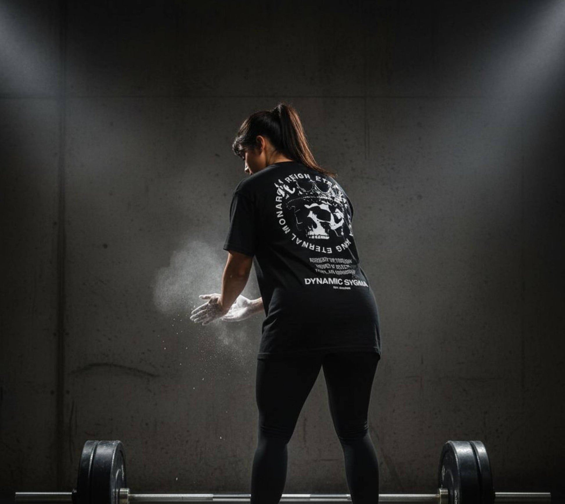 Person preparing to lift weights with a barbell in a dark room.