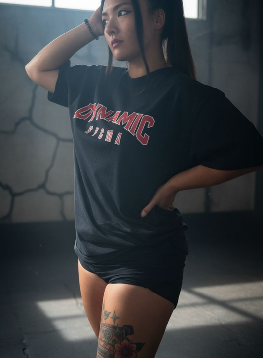 Person wearing a black t-shirt with 'Dynamic' printed on it, standing indoors.