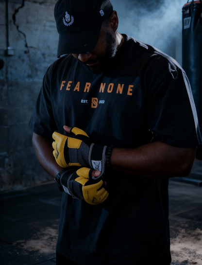 Person wearing a 'Fear None' t-shirt and gloves in a dark setting