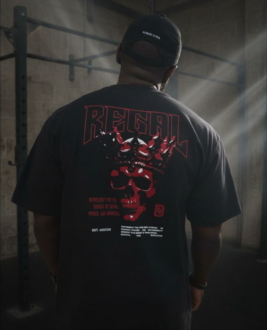 Person wearing a black t-shirt with red and white graphics and text, standing in a dimly lit room.