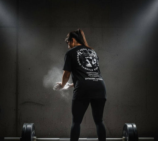 Person preparing to lift weights with a barbell in a dark room.